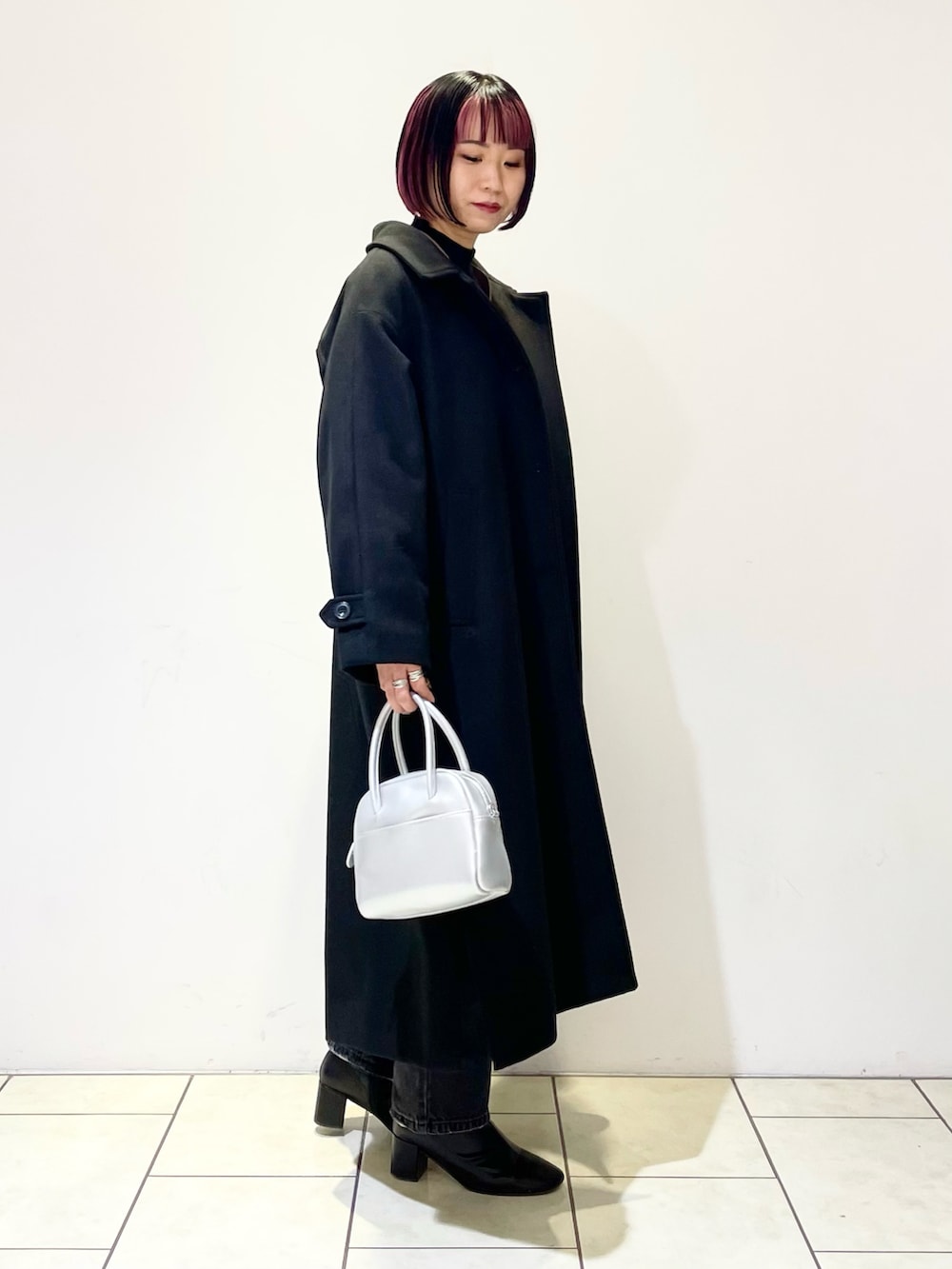 ブラック系のチェスターコート、ブラウン系のニット/セーター、ブラック系のニット/セーターを着用したレディースの春コーディネートの3枚目の写真