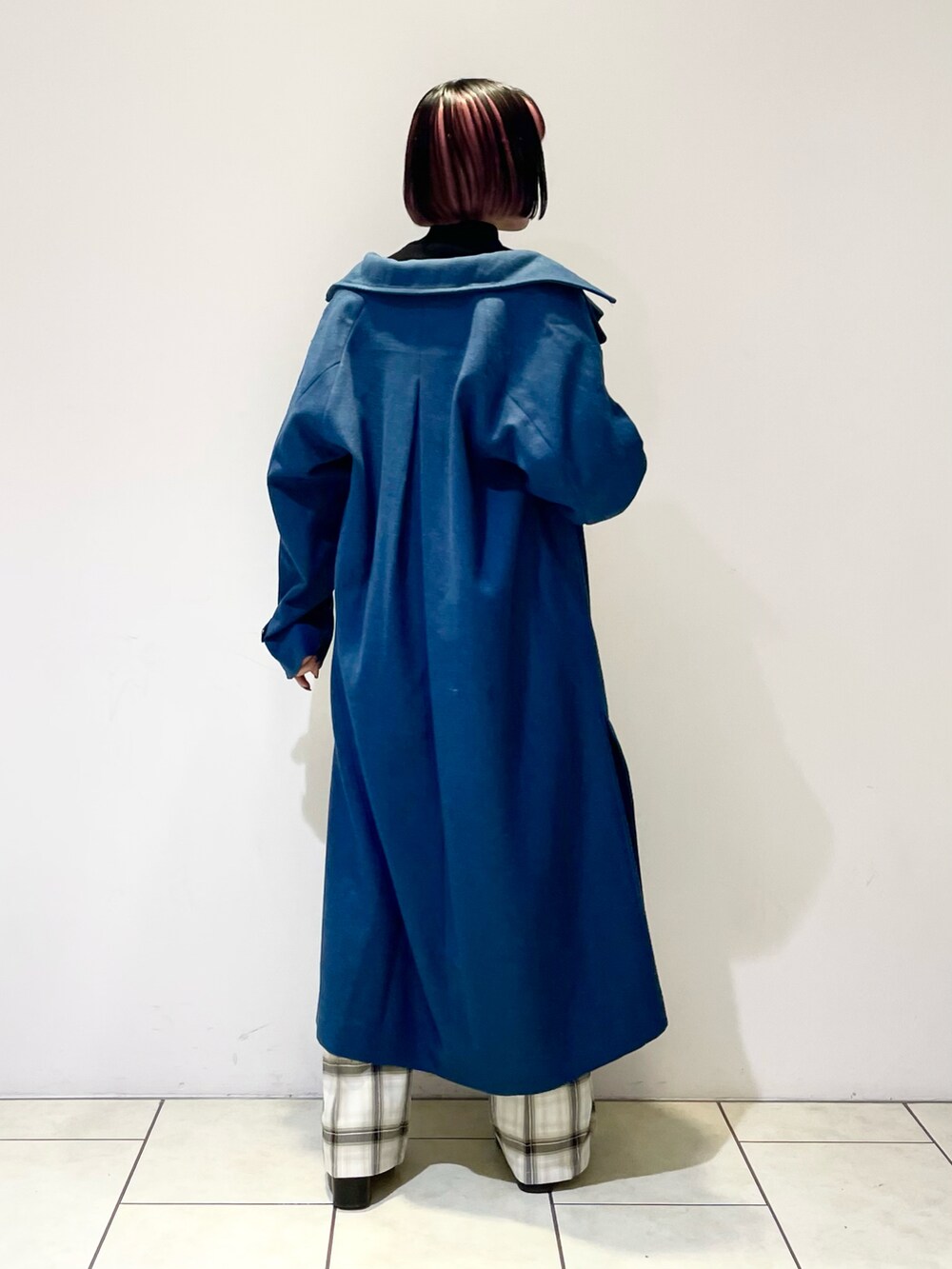 グリーン系のチェスターコート、ブラック系のニット/セーター、ホワイト系のその他パンツを着用したレディースの冬コーディネートの4枚目の写真