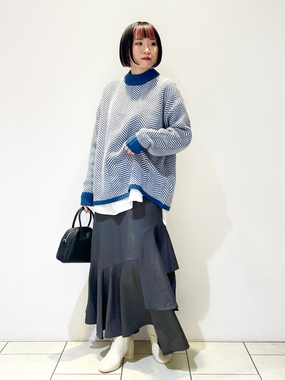 グリーン系のニット/セーター、ホワイト系のTシャツ/カットソー、ブラック系のボストンバッグを着用したレディースの春コーディネートの2枚目の写真