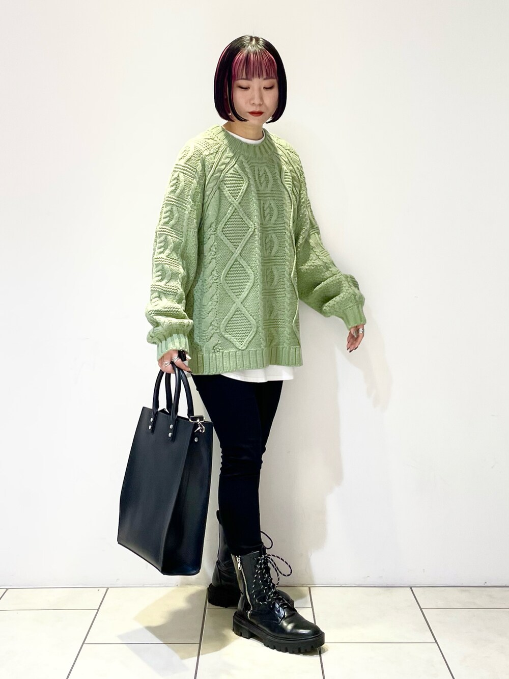 グリーン系のニット/セーター、ホワイト系のTシャツ/カットソー、ブラック系のデニムパンツを着用したレディースの冬コーディネートの3枚目の写真