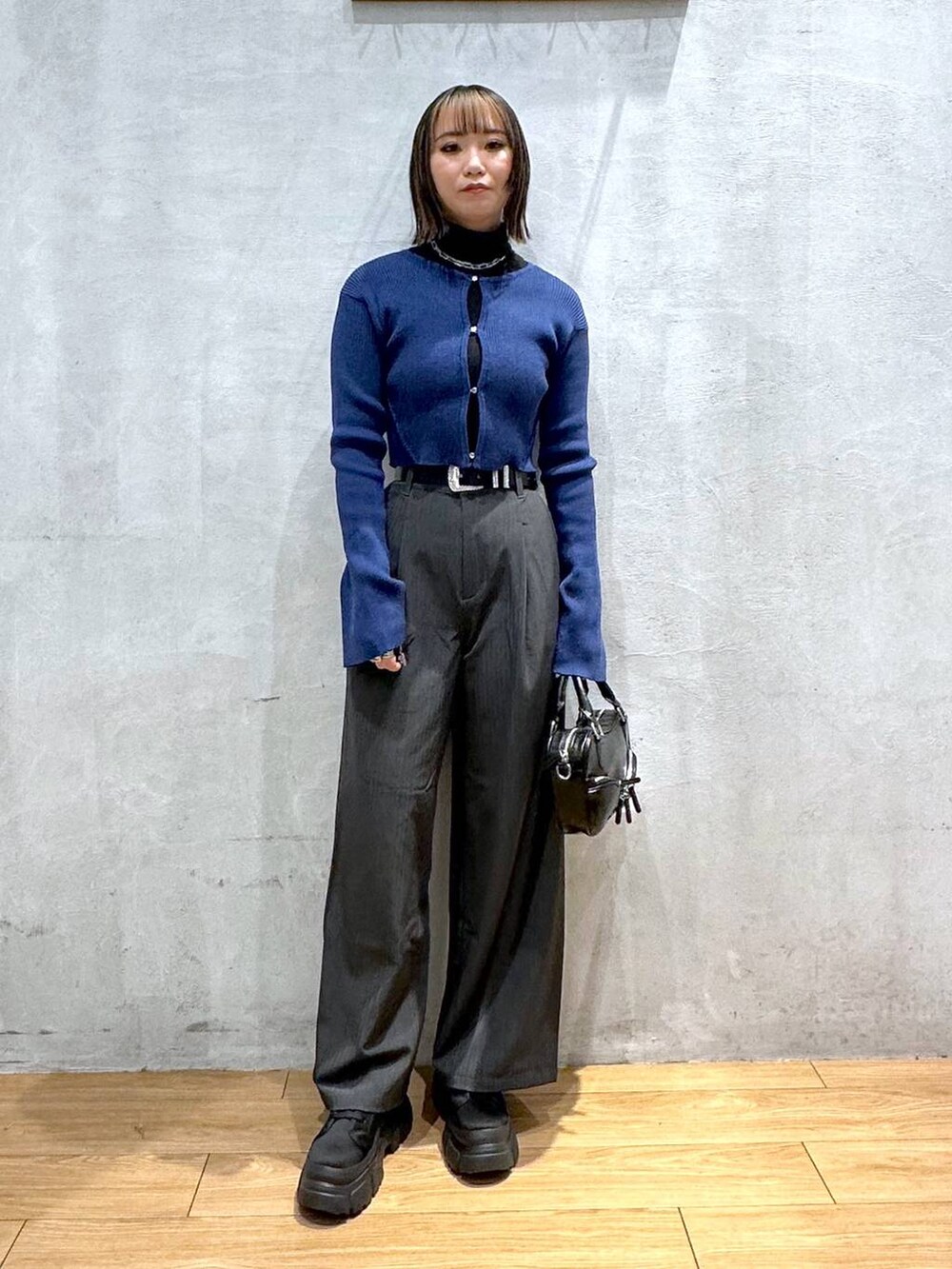 グレー系のスラックス、ブラック系のボストンバッグ、ブラック系のブーツを着用したレディースの冬コーディネートの2枚目の写真