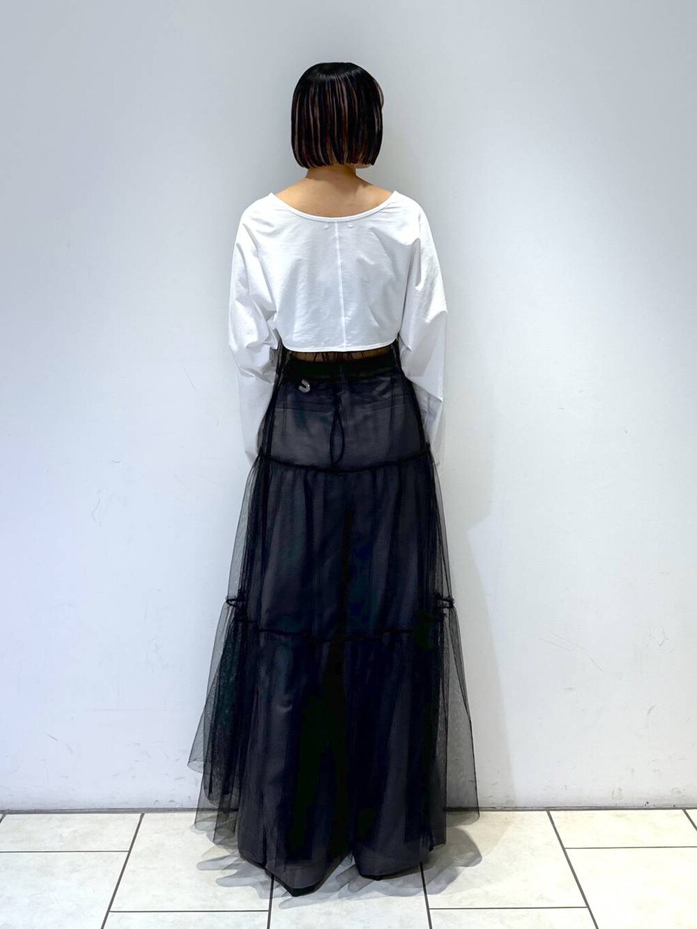 ブルー系のキャミソール、ブラック系のワンピース、グレー系のスラックスを着用したレディースの夏コーディネートの4枚目の写真