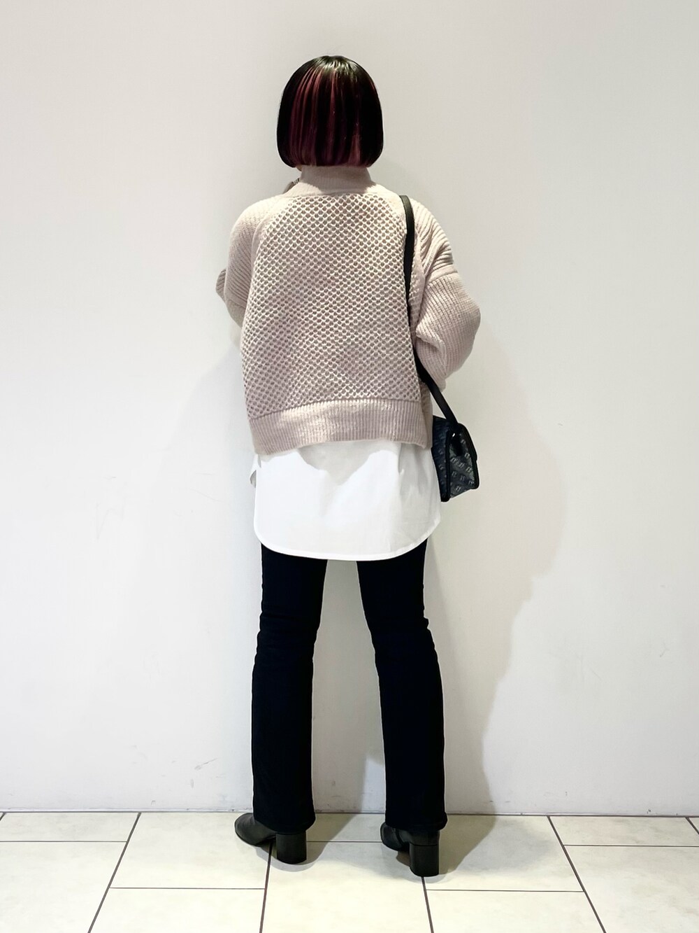 ベージュ系のニット/セーター、ホワイト系のTシャツ/カットソー、ブラック系のショルダーバッグを着用したレディースの冬コーディネートの3枚目の写真