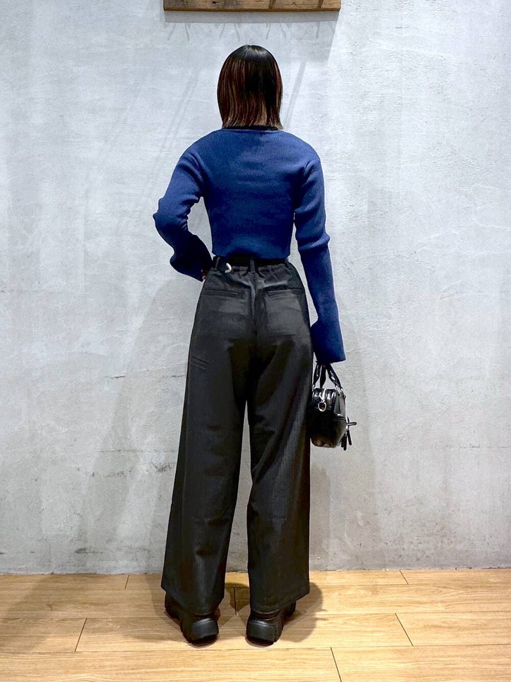 グレー系のスラックス、ブラック系のボストンバッグ、ブラック系のブーツを着用したレディースの冬コーディネートの4枚目の写真