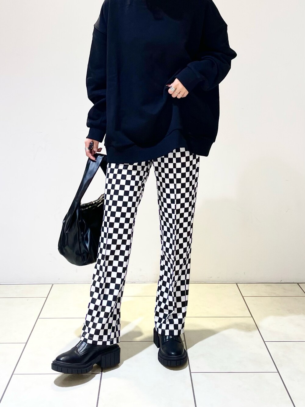 ブラック系のハンドバッグ、ブラック系のブーツ、ブラック系のスウェットを着用したレディースの冬コーディネートの4枚目の写真