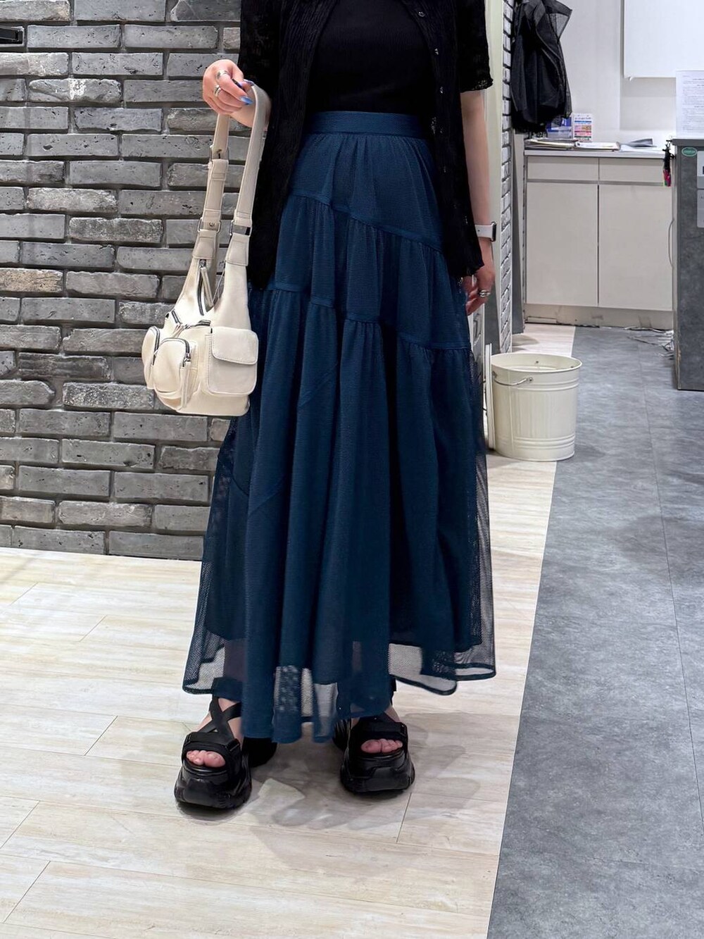 ブラック系のサンダル、ホワイト系のショルダーバッグ、ブルー系のスカートを着用したレディースの春コーディネートの6枚目の写真