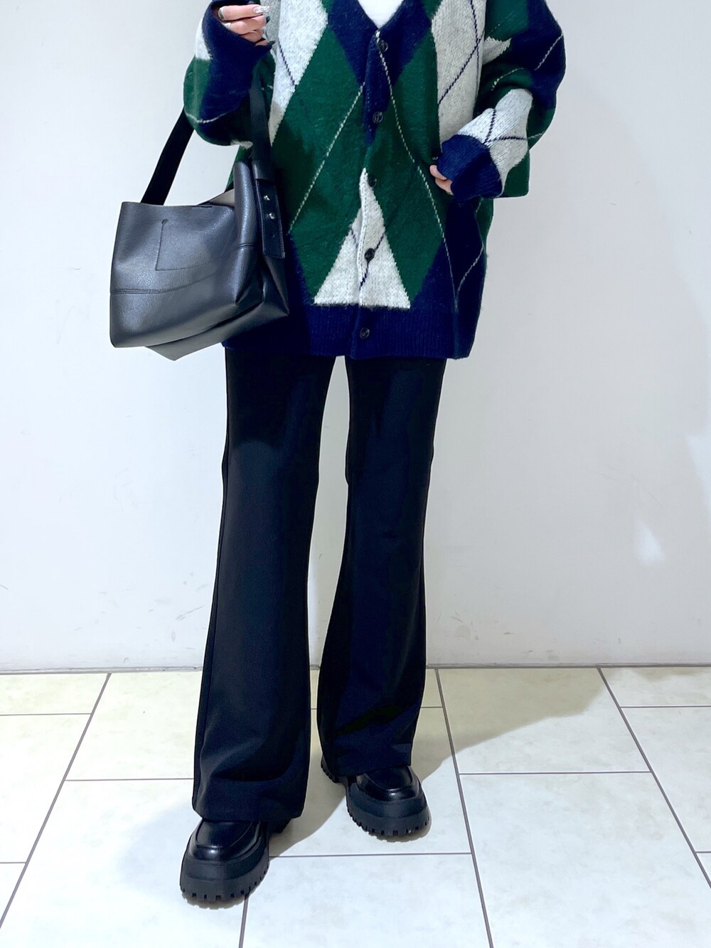 グリーン系のカーディガン/ボレロ、ホワイト系のキャミソール、ブラック系のスラックスを着用したレディースの秋コーディネートの3枚目の写真