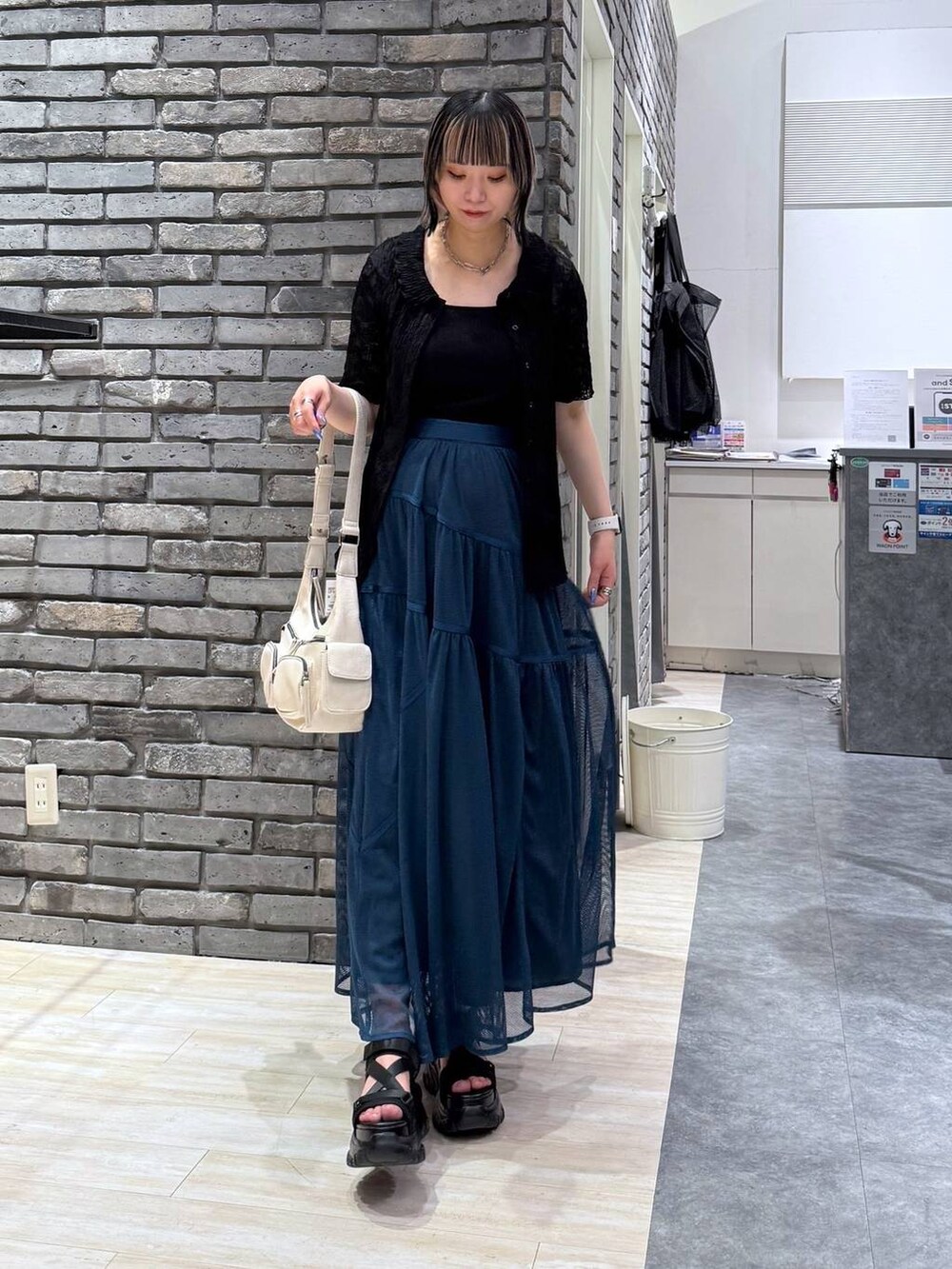 ブラック系のサンダル、ホワイト系のショルダーバッグ、ブルー系のスカートを着用したレディースの春コーディネートの3枚目の写真