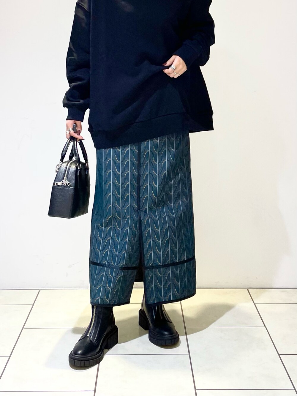 ブラック系のスウェット、ブラック系のショルダーバッグ、グリーン系のスカートを着用したレディースの冬コーディネートの4枚目の写真