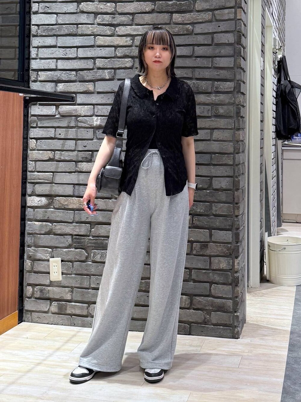 ブラック系のショルダーバッグ、ブラック系のシャツ/ブラウス、グレー系のスウェットパンツを着用したレディースの春コーディネートの2枚目の写真