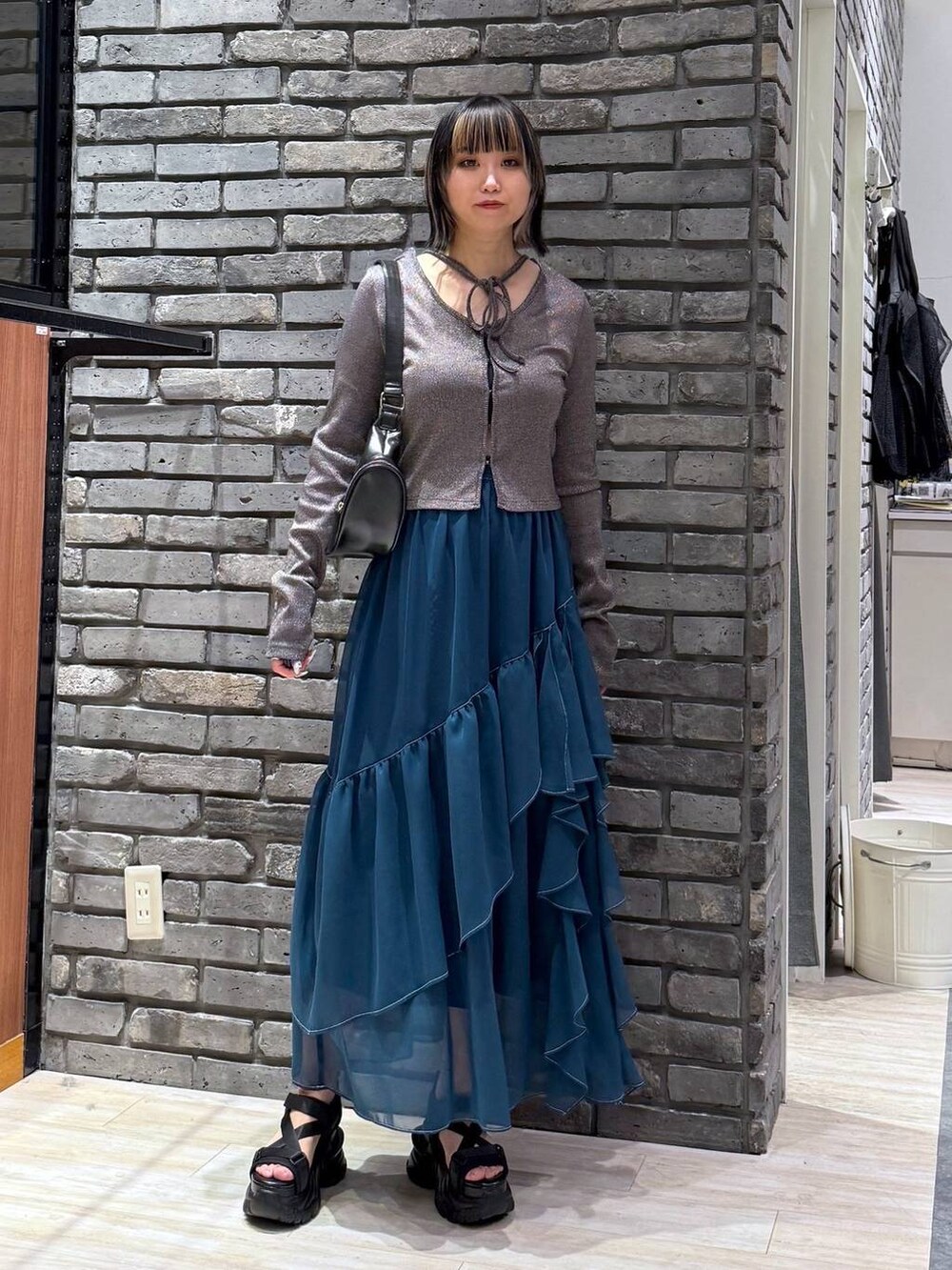 グリーン系のスカート、ブラック系のサンダル、ブラック系のショルダーバッグを着用したレディースの春コーディネートの3枚目の写真