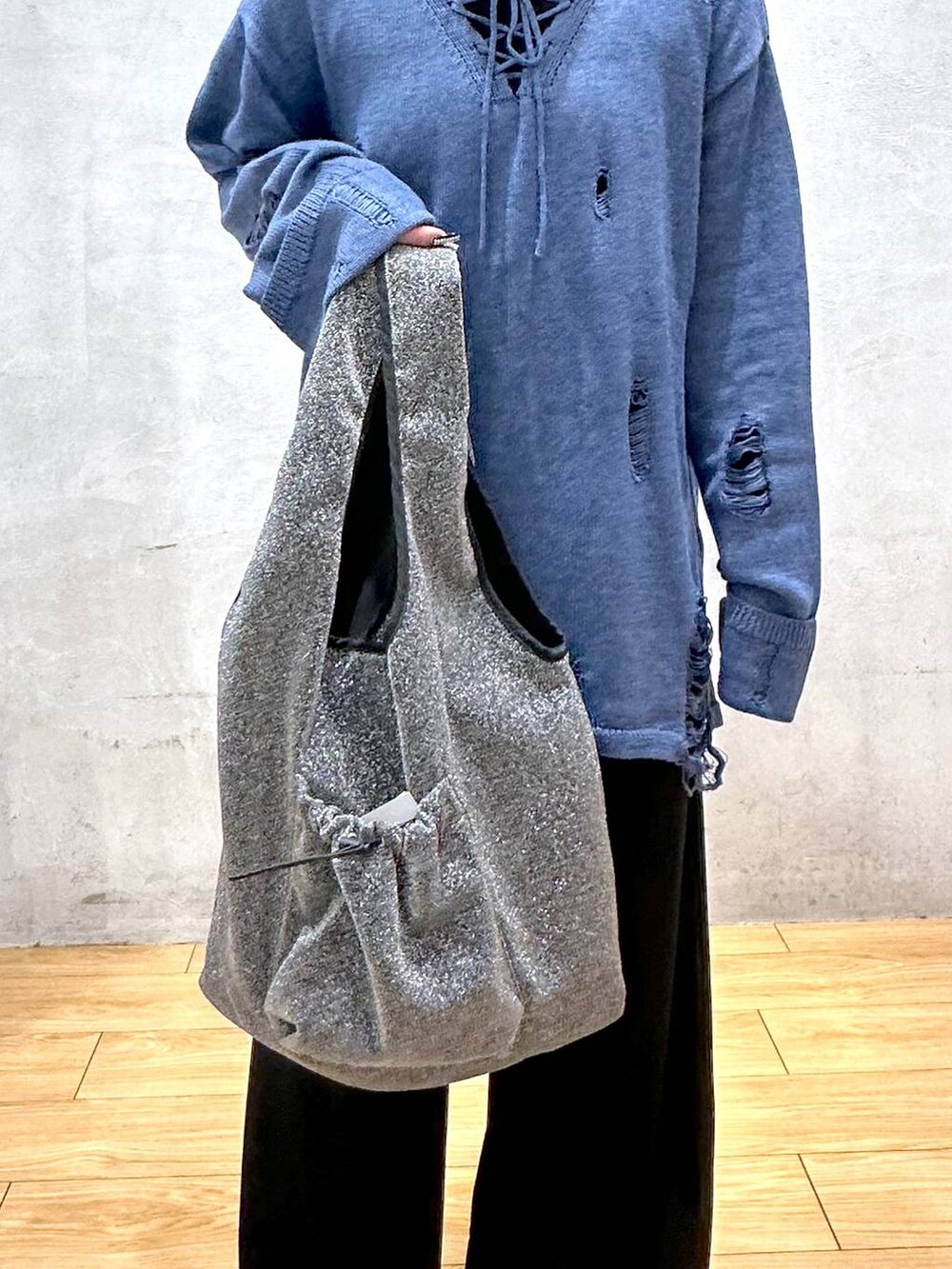 ブラック系のスラックス、ブルー系のニット/セーター、ブラック系のトートバッグを着用したレディースの冬コーディネートの4枚目の写真