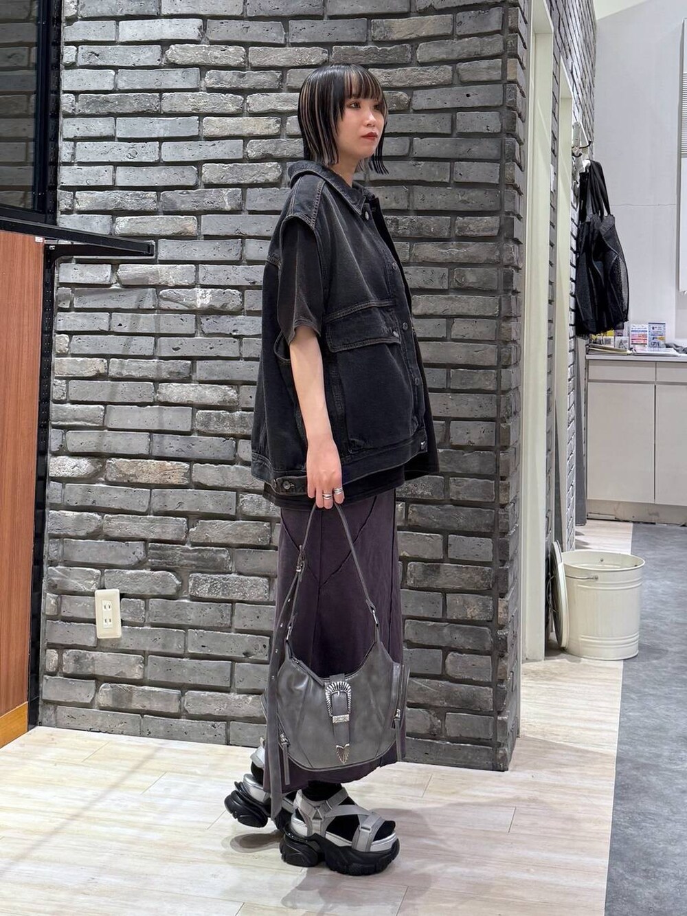 グレー系のサンダル、グレー系のショルダーバッグ、ブラック系のデニムジャケットを着用したレディースの春コーディネートの3枚目の写真