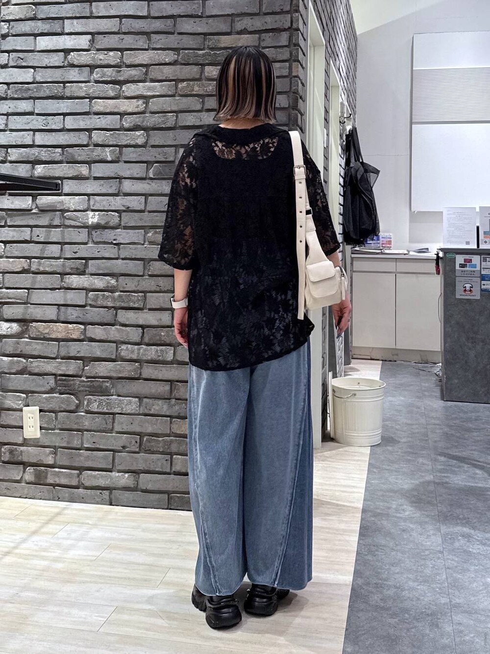 ブラック系のサンダル、ブルー系のデニムパンツ、ホワイト系のショルダーバッグを着用したレディースの春コーディネートの4枚目の写真