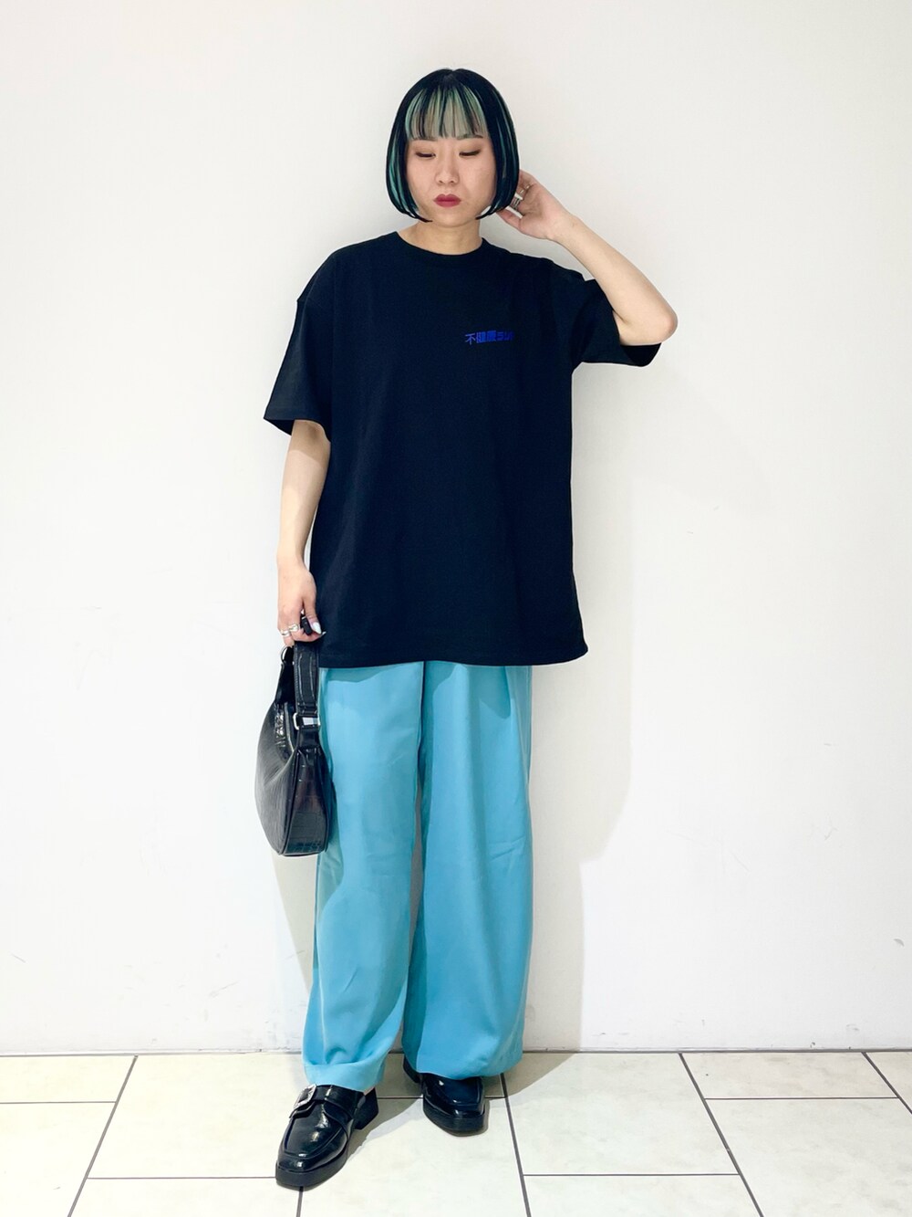 ブルー系のスラックス、ブラック系のショルダーバッグ、ブラック系のローファーを着用したレディースの夏コーディネートの3枚目の写真