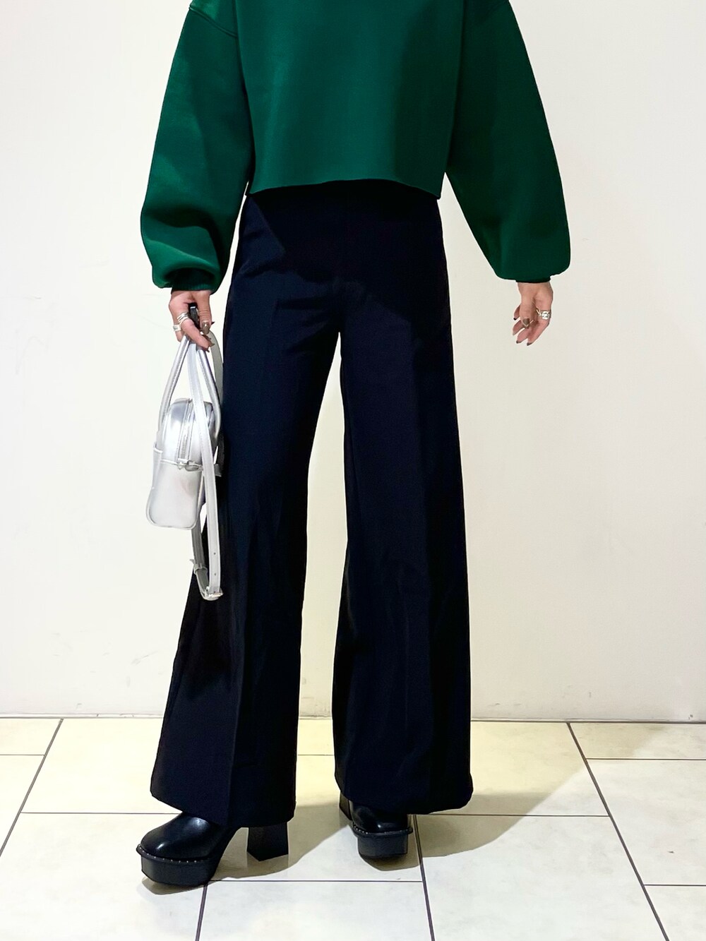 グリーン系のニット/セーター、シルバー系のボストンバッグ、ブラック系のスラックスを着用したレディースの春コーディネートの5枚目の写真