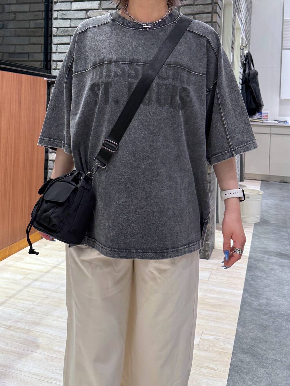 ブラック系のショルダーバッグ、ブラック系のTシャツ/カットソー、ホワイト系のスウェットパンツを着用したレディースの春コーディネートの4枚目の写真