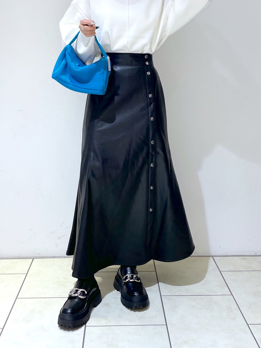 ホワイト系のニット/セーター、ブルー系のハンドバッグ、ブラック系のローファーを着用したレディースの秋コーディネートの5枚目の写真