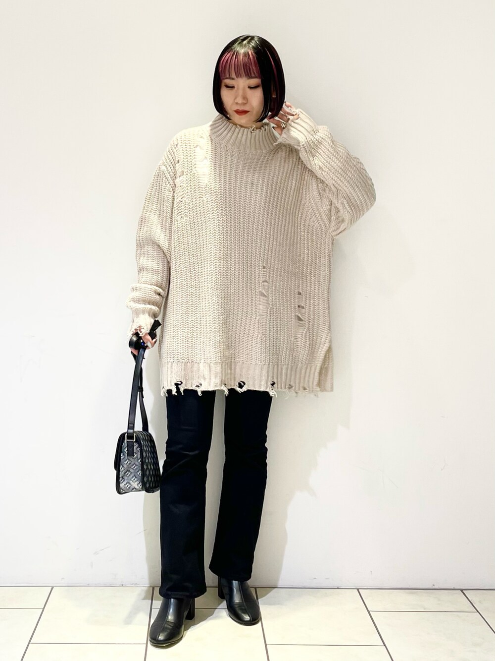 ベージュ系のニット/セーター、ホワイト系のTシャツ/カットソー、ブラック系のショルダーバッグを着用したレディースの冬コーディネートの2枚目の写真