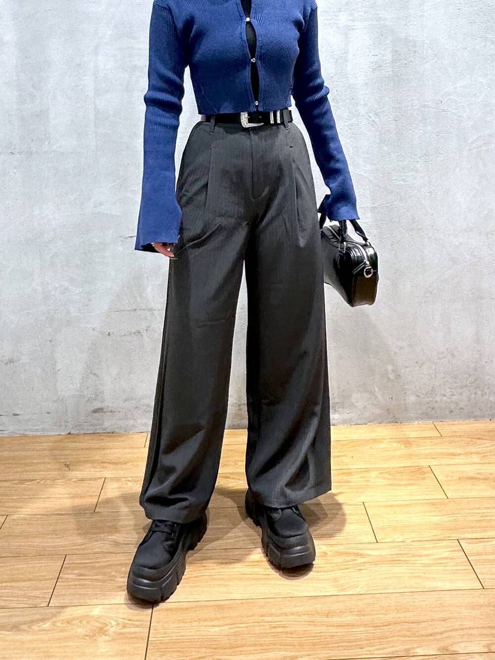 グレー系のスラックス、ブラック系のボストンバッグ、ブラック系のブーツを着用したレディースの冬コーディネートの5枚目の写真