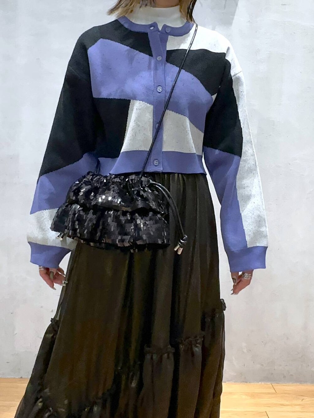 ブラック系のカーディガン/ボレロ、ブラック系のローファー、ブラック系のスカートを着用したレディースの春コーディネートの5枚目の写真