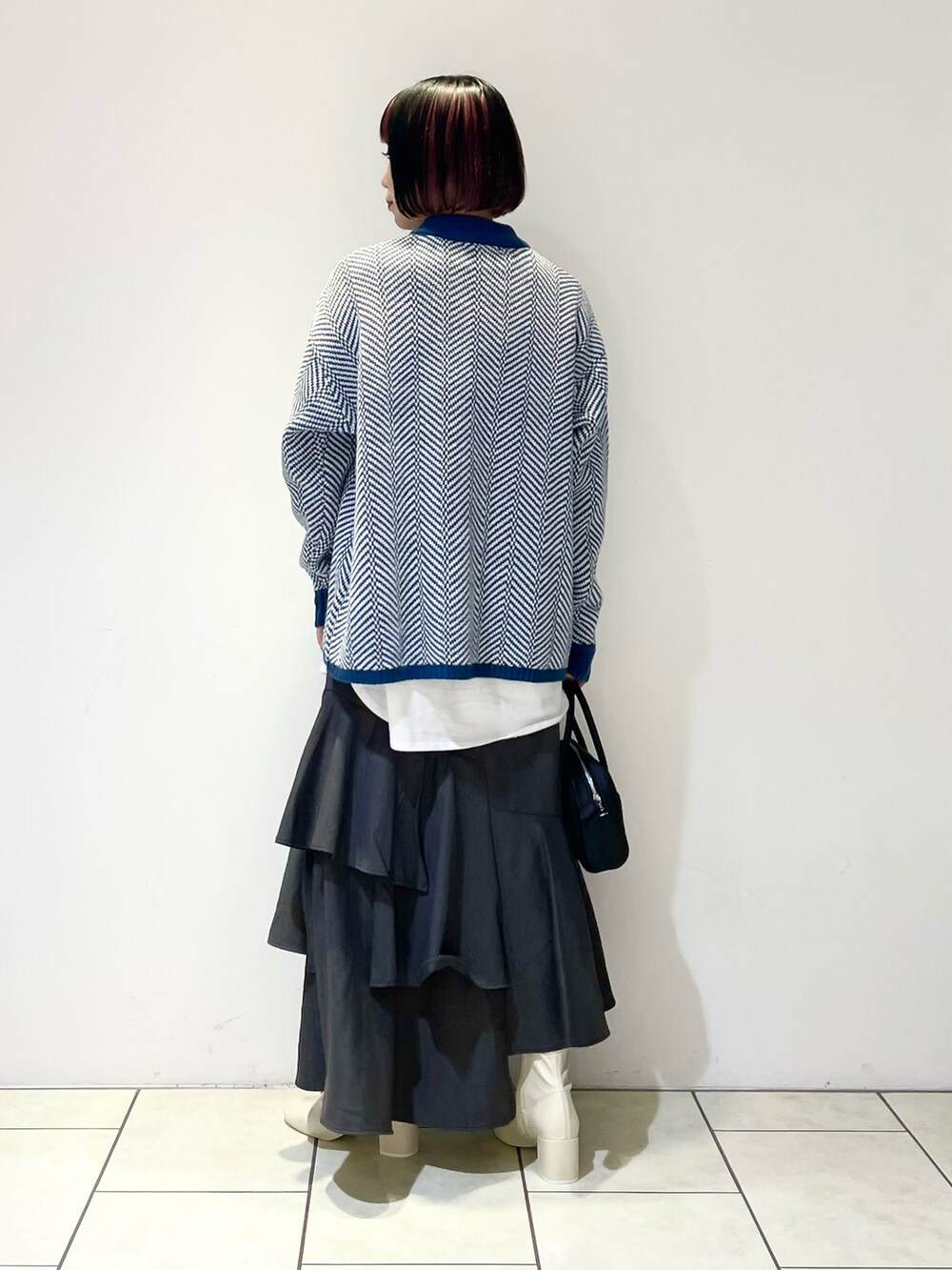 グリーン系のニット/セーター、ホワイト系のTシャツ/カットソー、ブラック系のボストンバッグを着用したレディースの春コーディネートの3枚目の写真