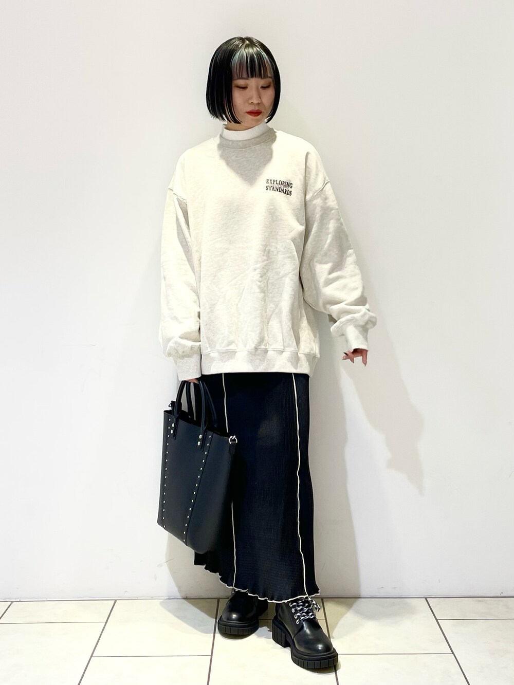 ホワイト系のニット/セーター、ベージュ系のスウェット、ブラック系のショルダーバッグを着用したレディースの春コーディネートの2枚目の写真