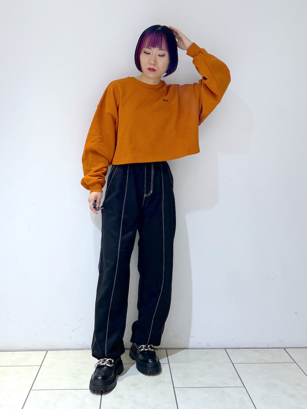 オレンジ系のスウェット、ブラック系のその他パンツ、ブラック系のローファーを着用したレディースの秋コーディネートの2枚目の写真