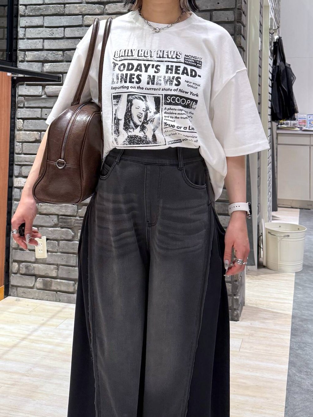 ブラウン系のボストンバッグ、ブラック系のデニムパンツ、ホワイト系のTシャツ/カットソーを着用したレディースの春コーディネートの4枚目の写真