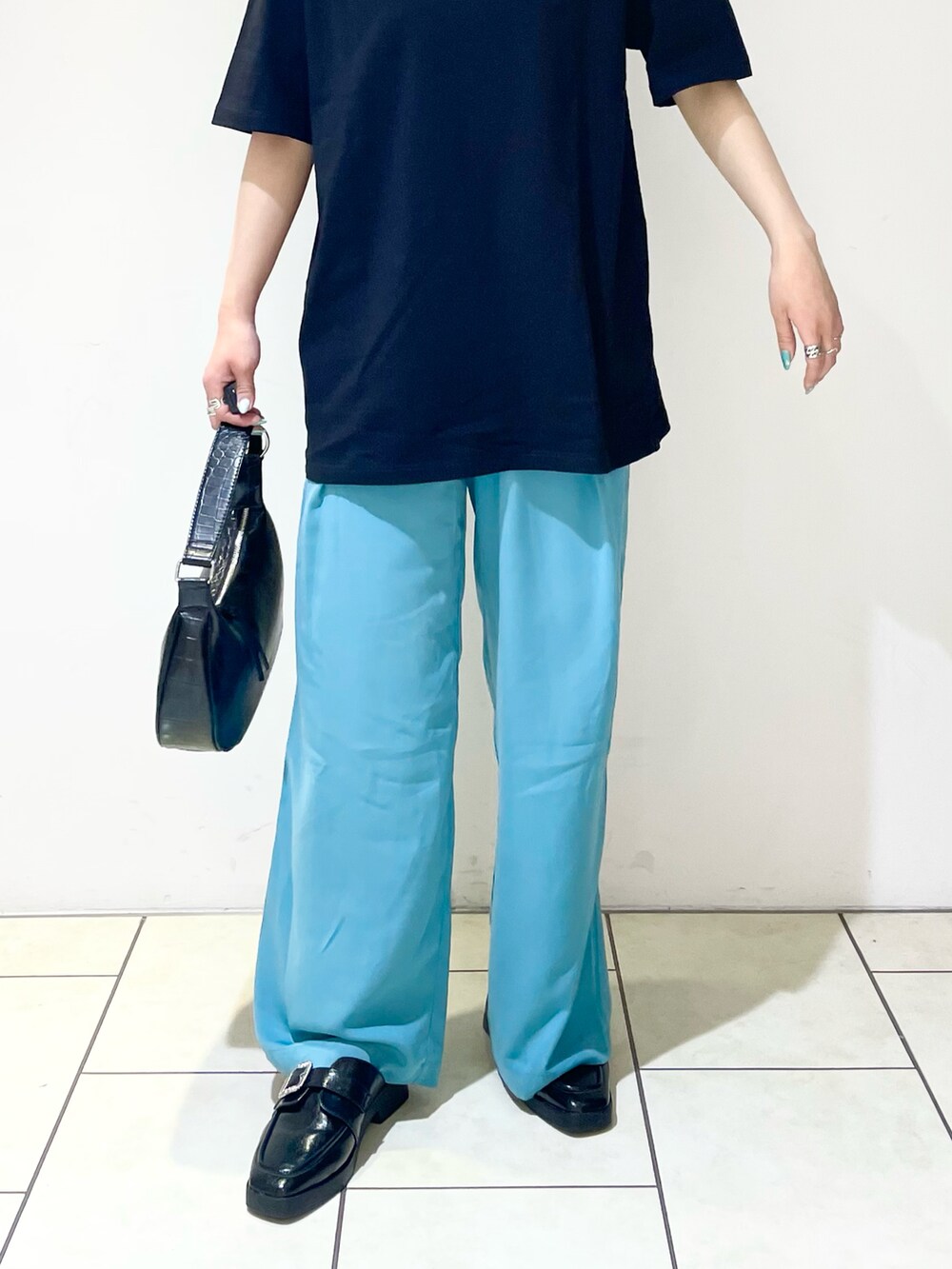 ブルー系のスラックス、ブラック系のショルダーバッグ、ブラック系のローファーを着用したレディースの夏コーディネートの5枚目の写真