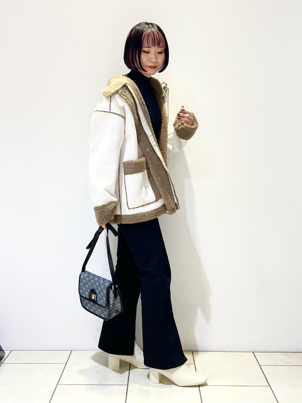 ベージュ系のブルゾン、ブラック系のニット/セーター、ブラック系のデニムパンツを着用したレディースの冬コーディネートの2枚目の写真