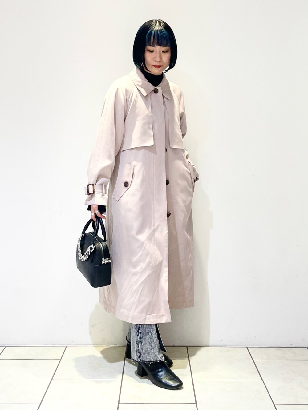 ベージュ系のトレンチコート、ブラック系のニット/セーター、ブラック系のデニムパンツを着用したレディースの春コーディネートの3枚目の写真