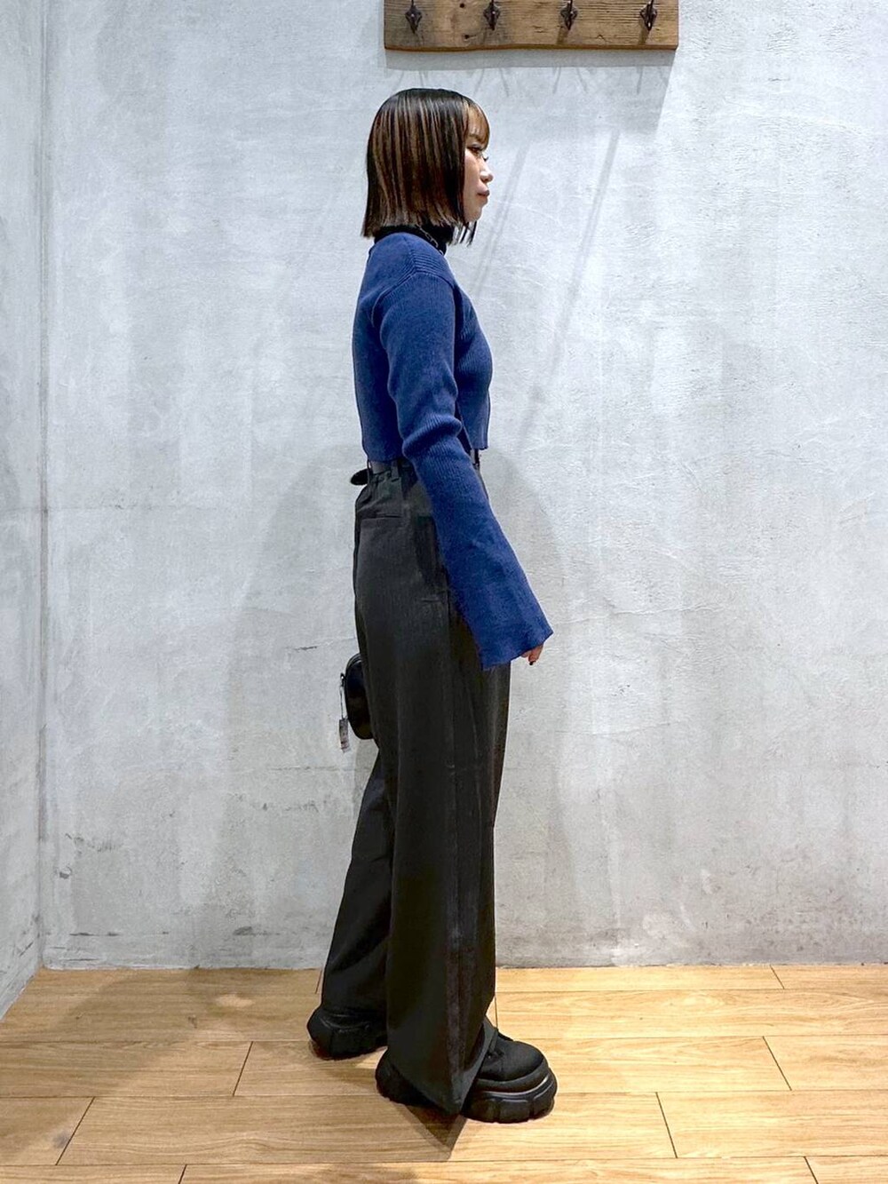 グレー系のスラックス、ブラック系のボストンバッグ、ブラック系のブーツを着用したレディースの冬コーディネートの3枚目の写真