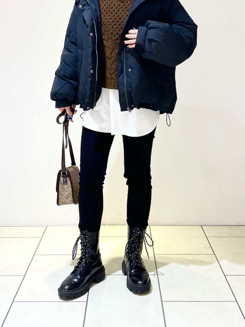 ブラック系のブルゾン、ホワイト系のTシャツ/カットソー、ブラウン系のニット/セーターを着用したレディースの冬コーディネートの5枚目の写真