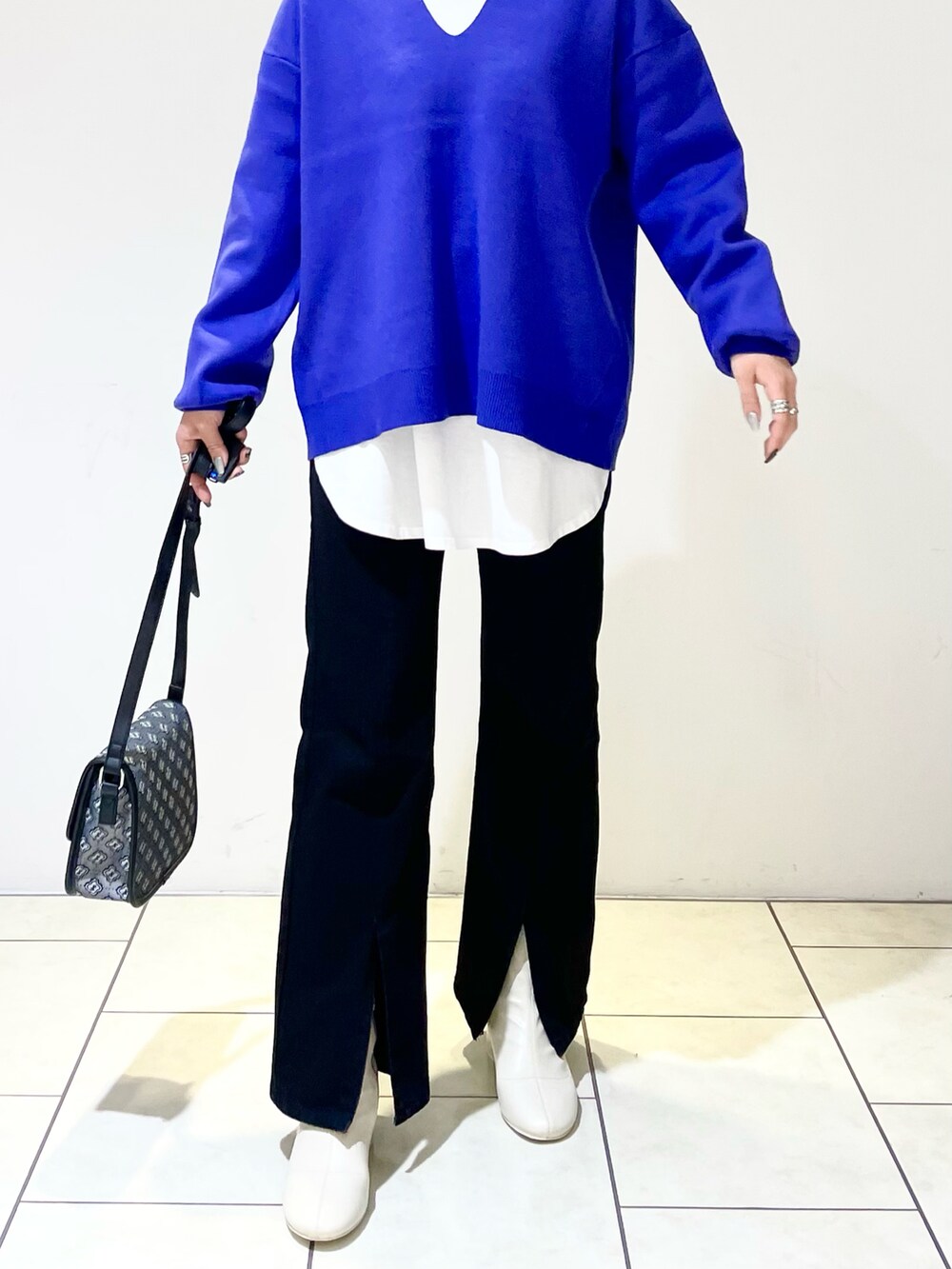 ブルー系のニット/セーター、ホワイト系のTシャツ/カットソー、ブラック系のショルダーバッグを着用したレディースの冬コーディネートの3枚目の写真