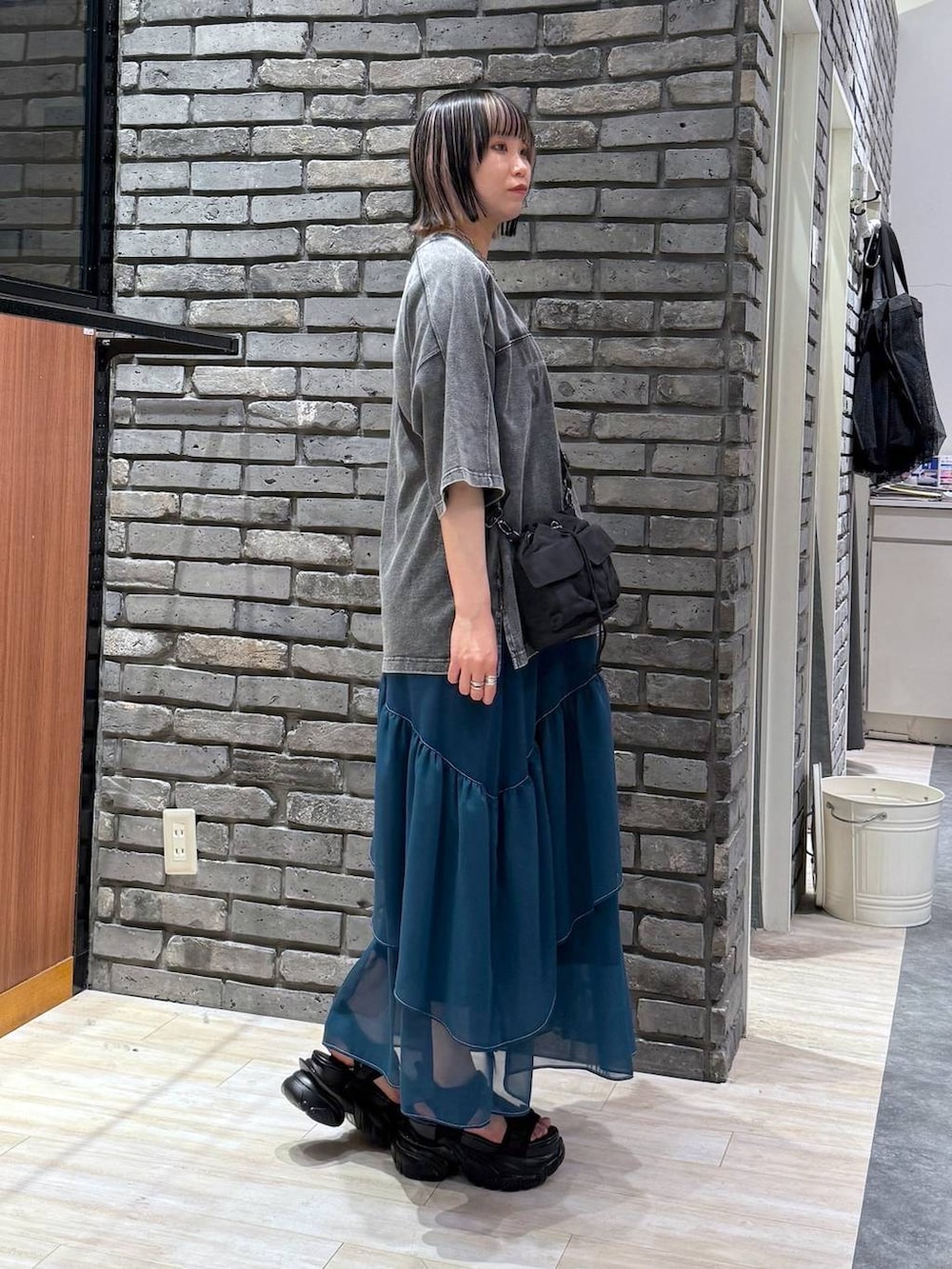 グリーン系のスカート、ブラック系のサンダル、ブラック系のショルダーバッグを着用したレディースの春コーディネートの3枚目の写真