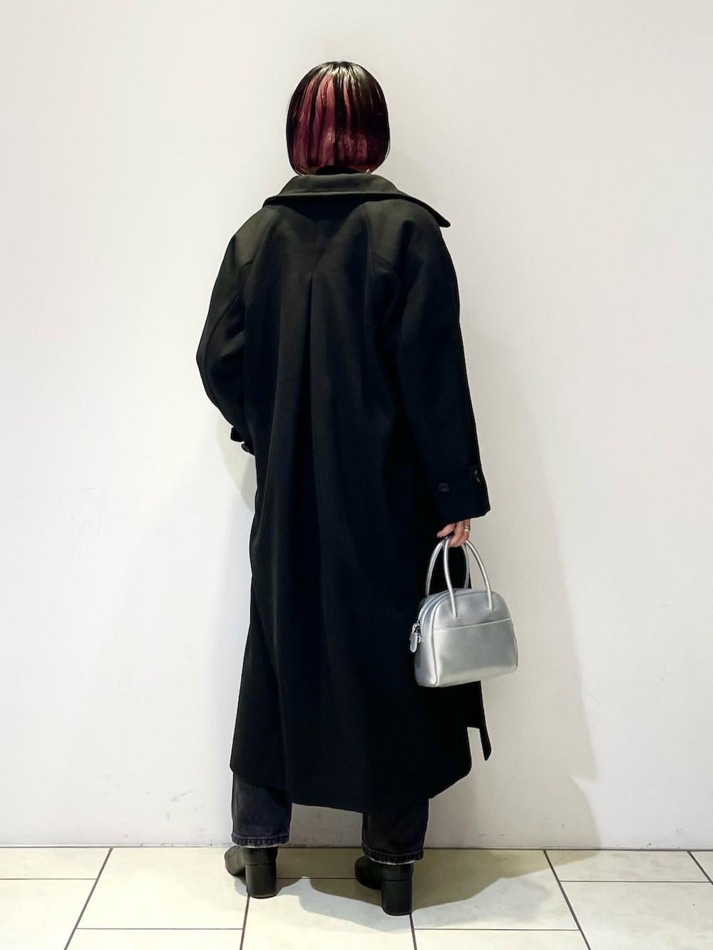 ブラック系のチェスターコート、ブラウン系のニット/セーター、ブラック系のニット/セーターを着用したレディースの春コーディネートの4枚目の写真