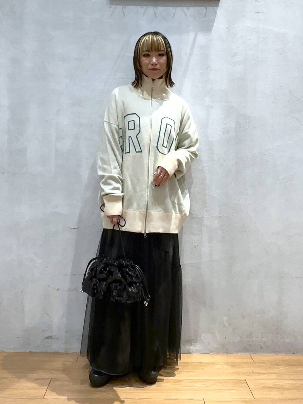 ベージュ系のニット/セーター、ブラック系のデニムパンツ、ブラック系のワンピースを着用したレディースの冬コーディネートの2枚目の写真