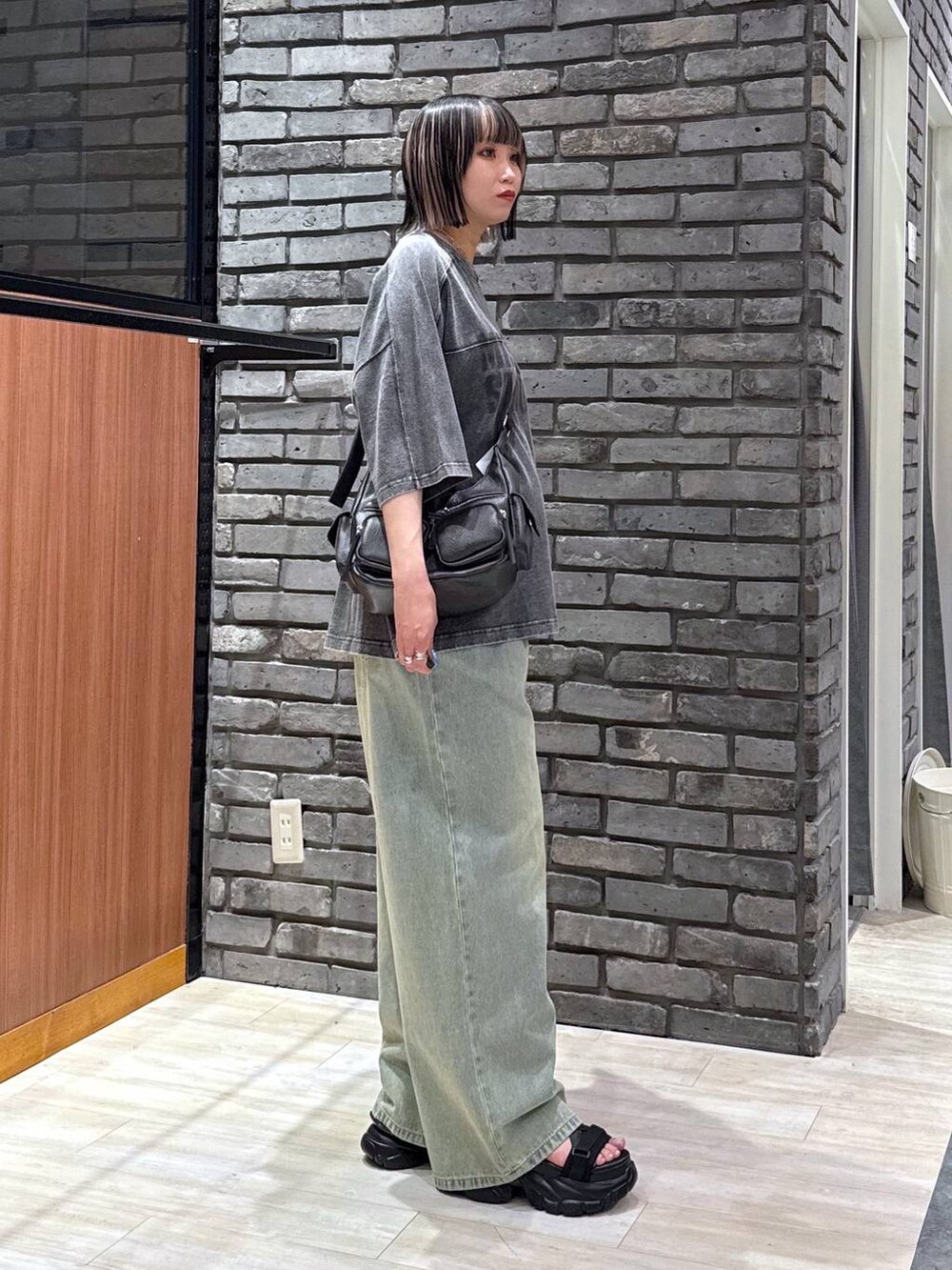 ブルー系のデニムパンツ、ブラック系のサンダル、ブラック系のTシャツ/カットソーを着用したレディースの春コーディネートの3枚目の写真