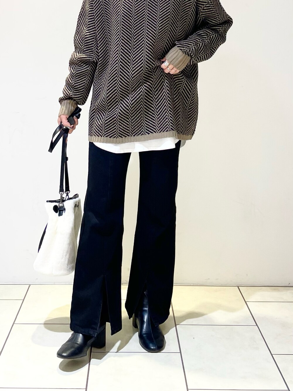 ブラウン系のニット/セーター、ホワイト系のTシャツ/カットソー、ブラック系のデニムパンツを着用したレディースの冬コーディネートの3枚目の写真