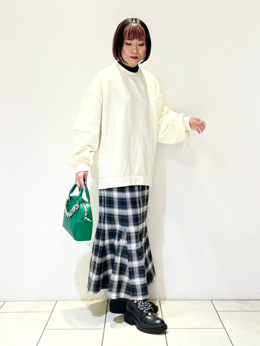 ホワイト系のスウェット、ブラック系のニット/セーター、グリーン系のショルダーバッグを着用したレディースの春コーディネートの3枚目の写真