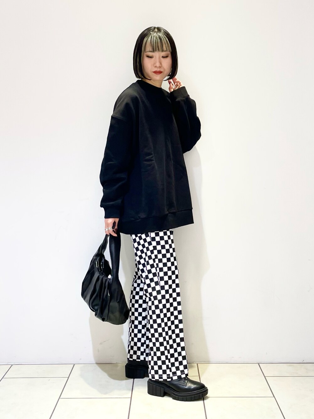 ブラック系のハンドバッグ、ブラック系のブーツ、ブラック系のスウェットを着用したレディースの冬コーディネートの3枚目の写真