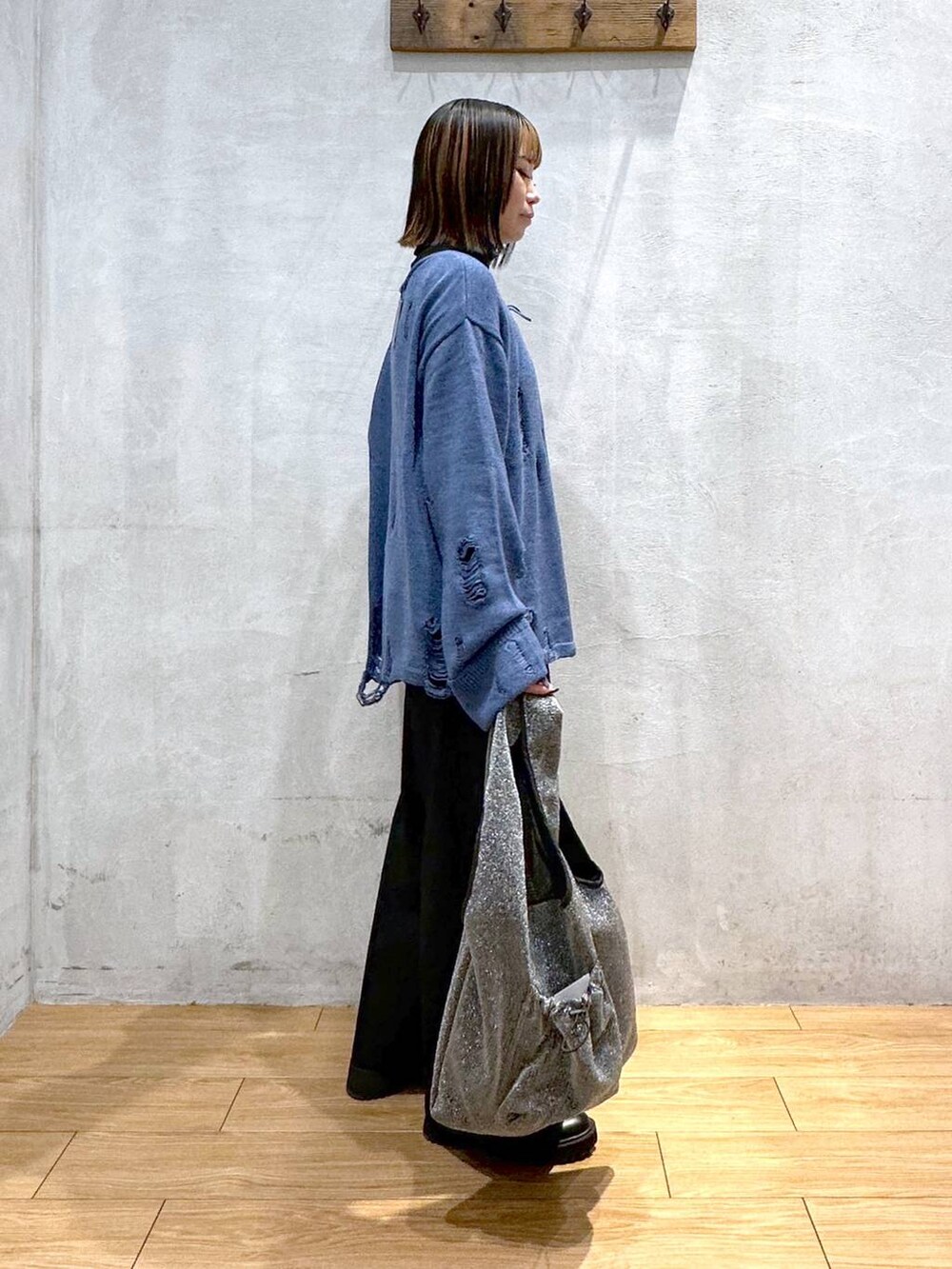 ブラック系のスラックス、ブルー系のニット/セーター、ブラック系のトートバッグを着用したレディースの冬コーディネートの2枚目の写真