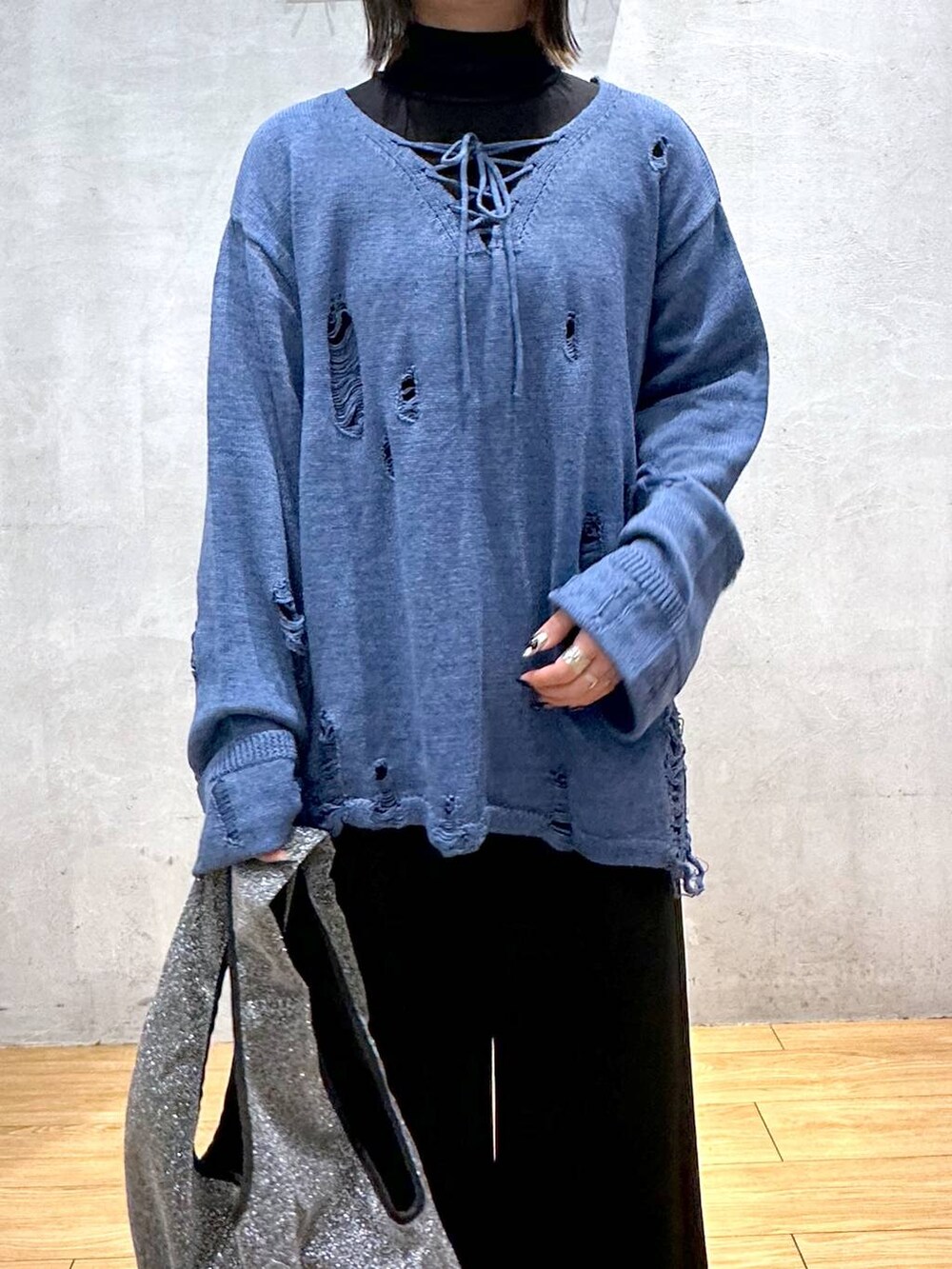 ブラック系のスラックス、ブルー系のニット/セーター、ブラック系のトートバッグを着用したレディースの冬コーディネートの3枚目の写真