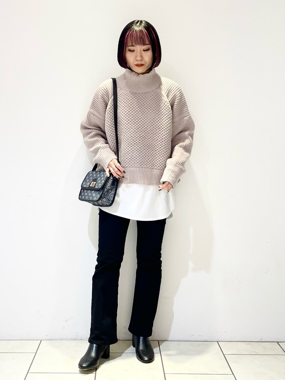 ベージュ系のニット/セーター、ホワイト系のTシャツ/カットソー、ブラック系のショルダーバッグを着用したレディースの冬コーディネートの2枚目の写真