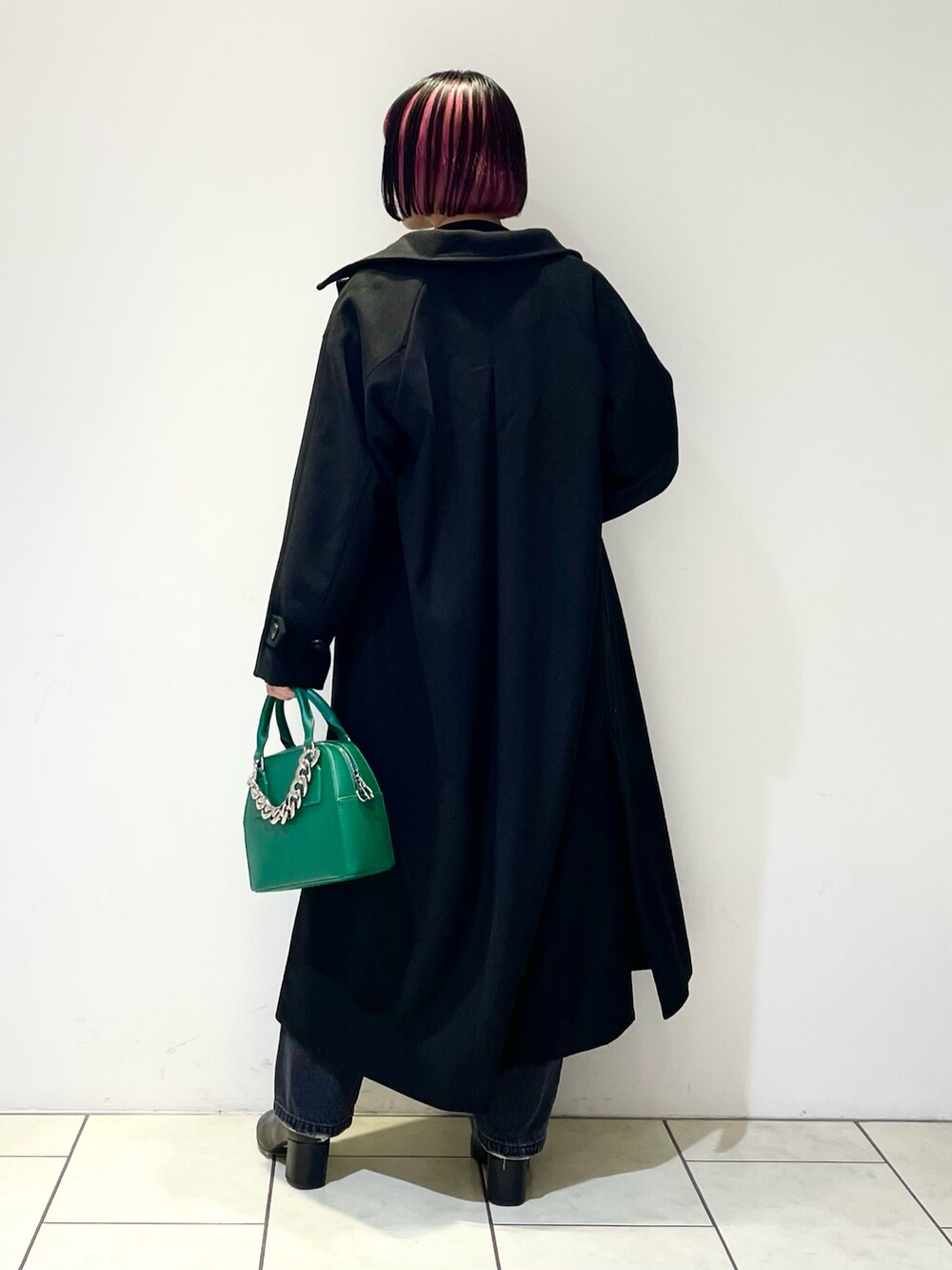 ブラック系のニット/セーター、ブラック系のチェスターコート、ブラック系のデニムパンツを着用したレディースの冬コーディネートの3枚目の写真