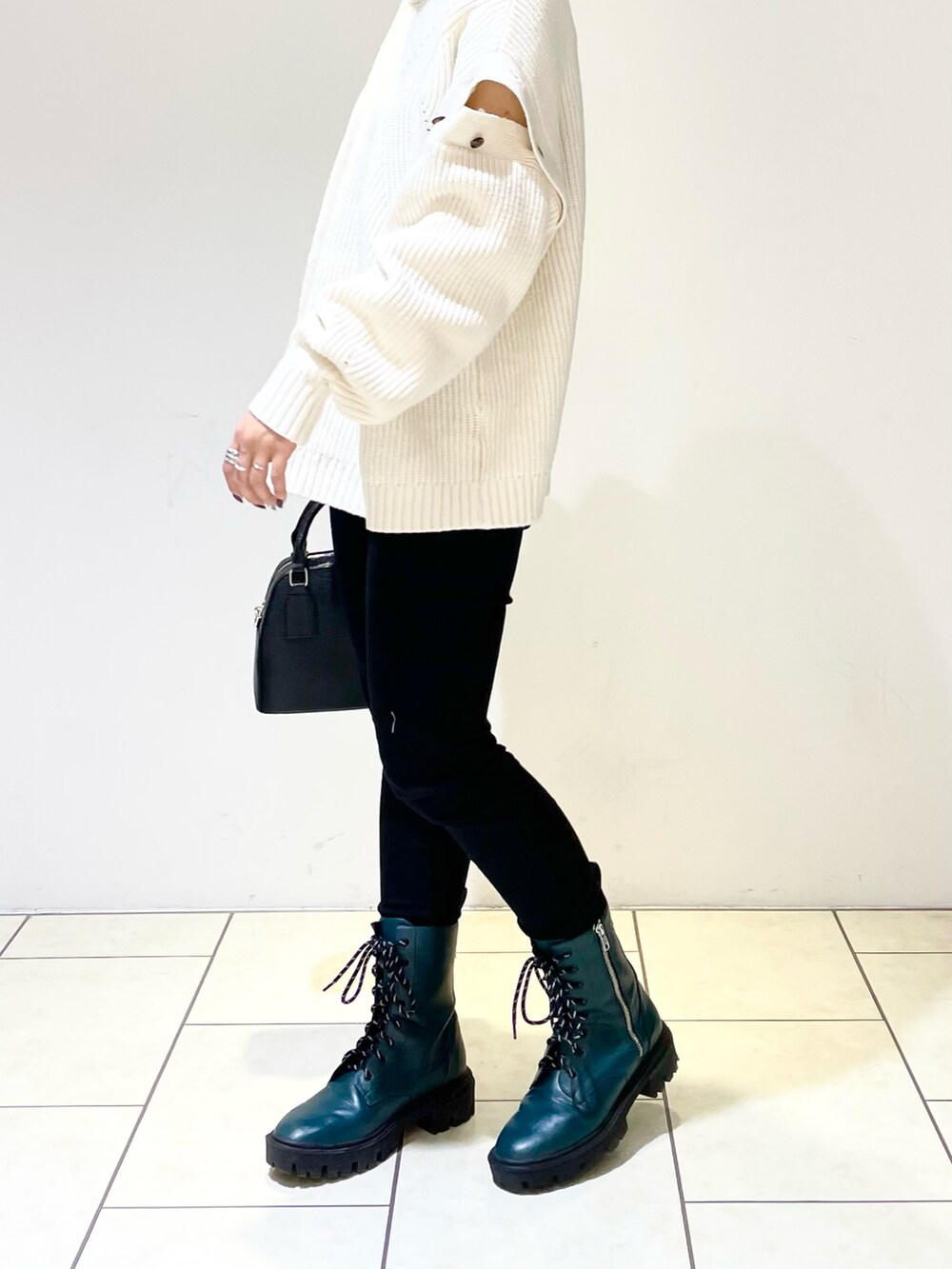 ホワイト系のニット/セーター、ブラック系のショルダーバッグ、ブラック系のデニムパンツを着用したレディースの冬コーディネートの4枚目の写真