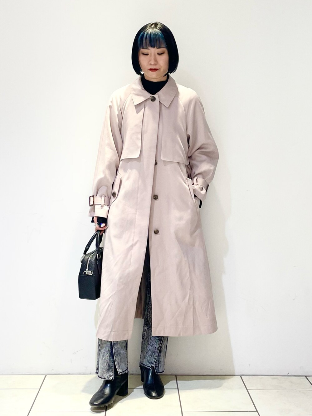 ベージュ系のトレンチコート、ブラック系のニット/セーター、ブラック系のデニムパンツを着用したレディースの春コーディネートの2枚目の写真