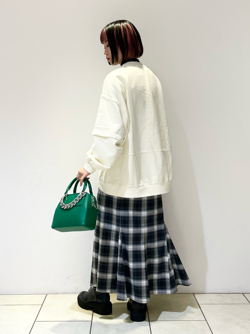 ホワイト系のスウェット、ブラック系のニット/セーター、グリーン系のショルダーバッグを着用したレディースの春コーディネートの4枚目の写真