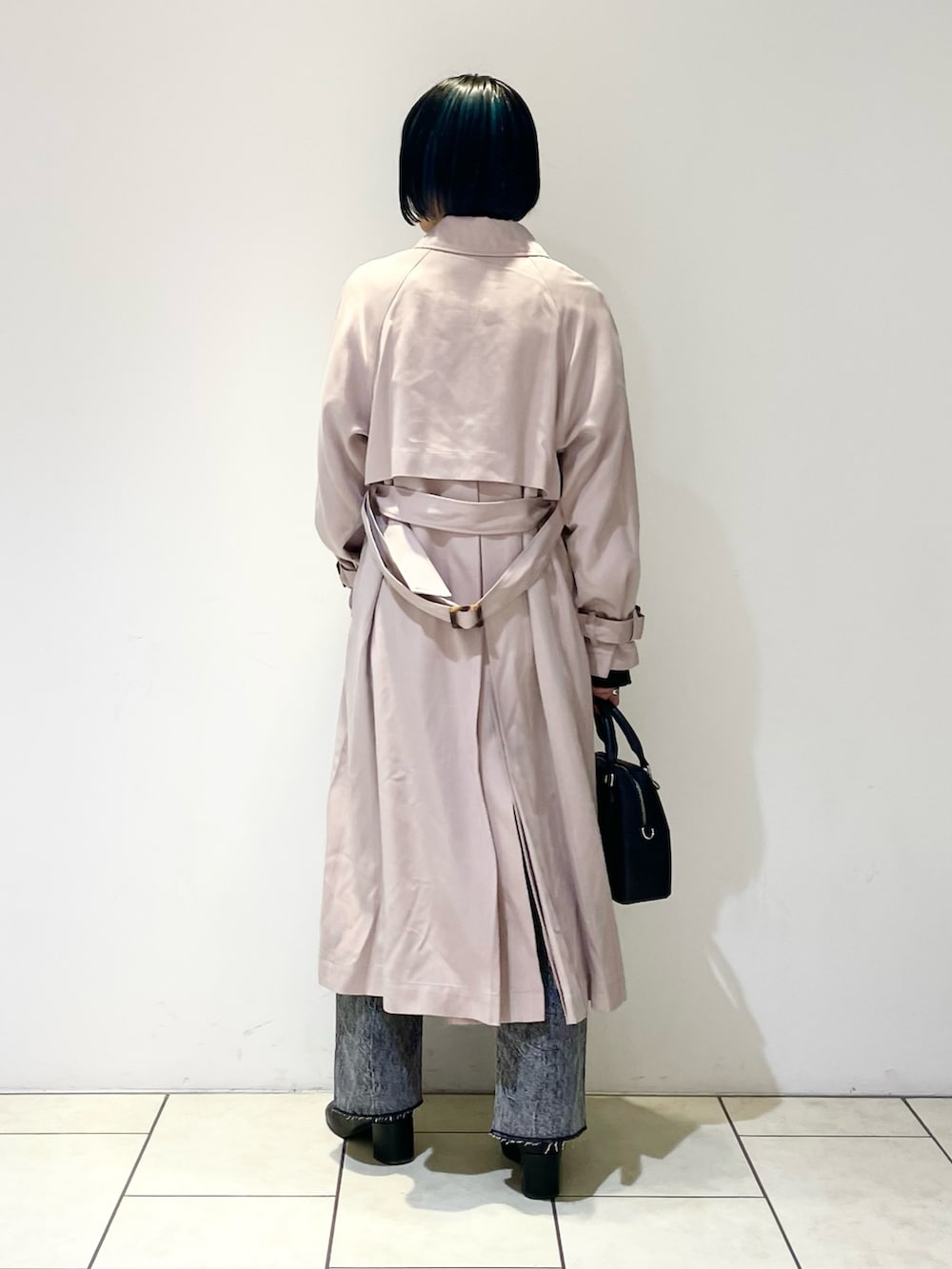 ベージュ系のトレンチコート、ブラック系のニット/セーター、ブラック系のデニムパンツを着用したレディースの春コーディネートの5枚目の写真